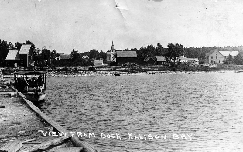 Ruckert Dock, Ellison Bay. Trinity Lutheran steeple and Disgarden Hotel to the far right and fanning mill for cleaning seeds to the left.